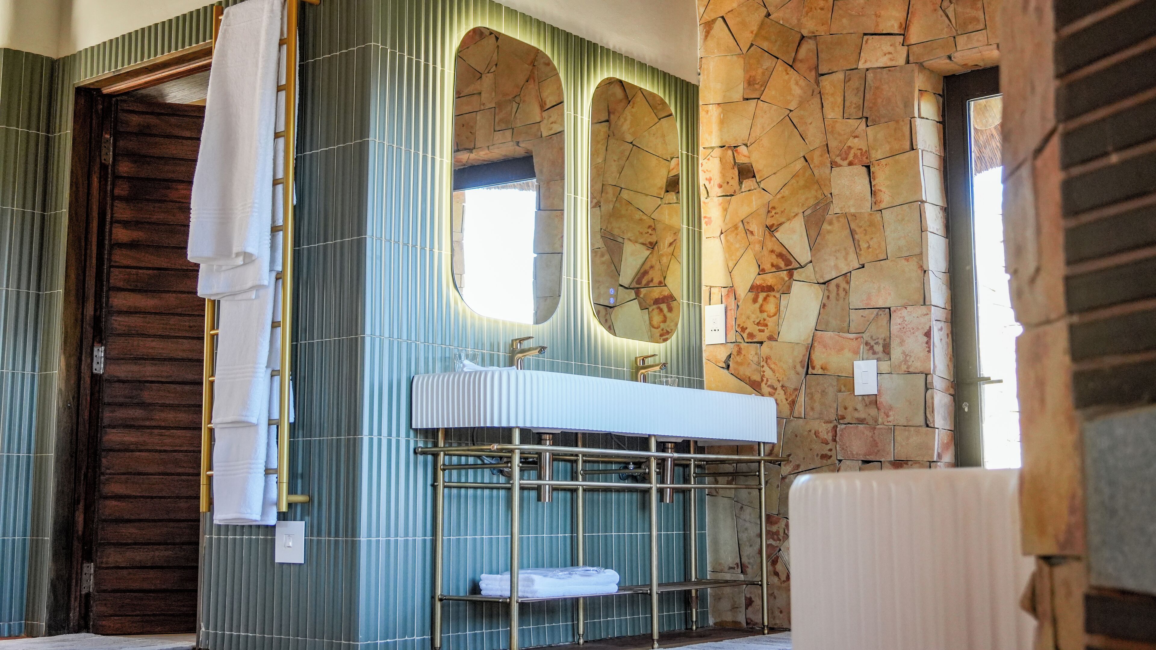 A bathroom with a stone wall, a wooden door, and a sink with a mirror.