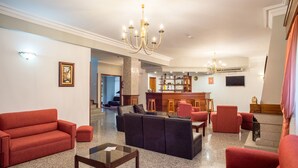 A spacious lobby with a bar area, seating arrangements, and a chandelier.