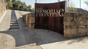 A stone wall and a metal gate with the inscription "ESPACO MEMORIA FRONTEIRA".