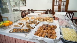 A buffet with various food items including pastries, fruits, and cheeses.