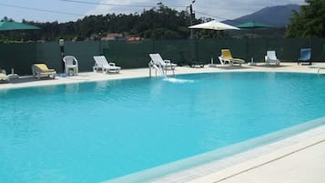 Una piscina al aire libre de temporada, sombrillas