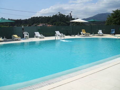 Una piscina al aire libre de temporada, sombrillas