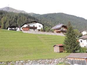 A mountain village with traditional wooden houses, stone walls, and a lush green landscape.