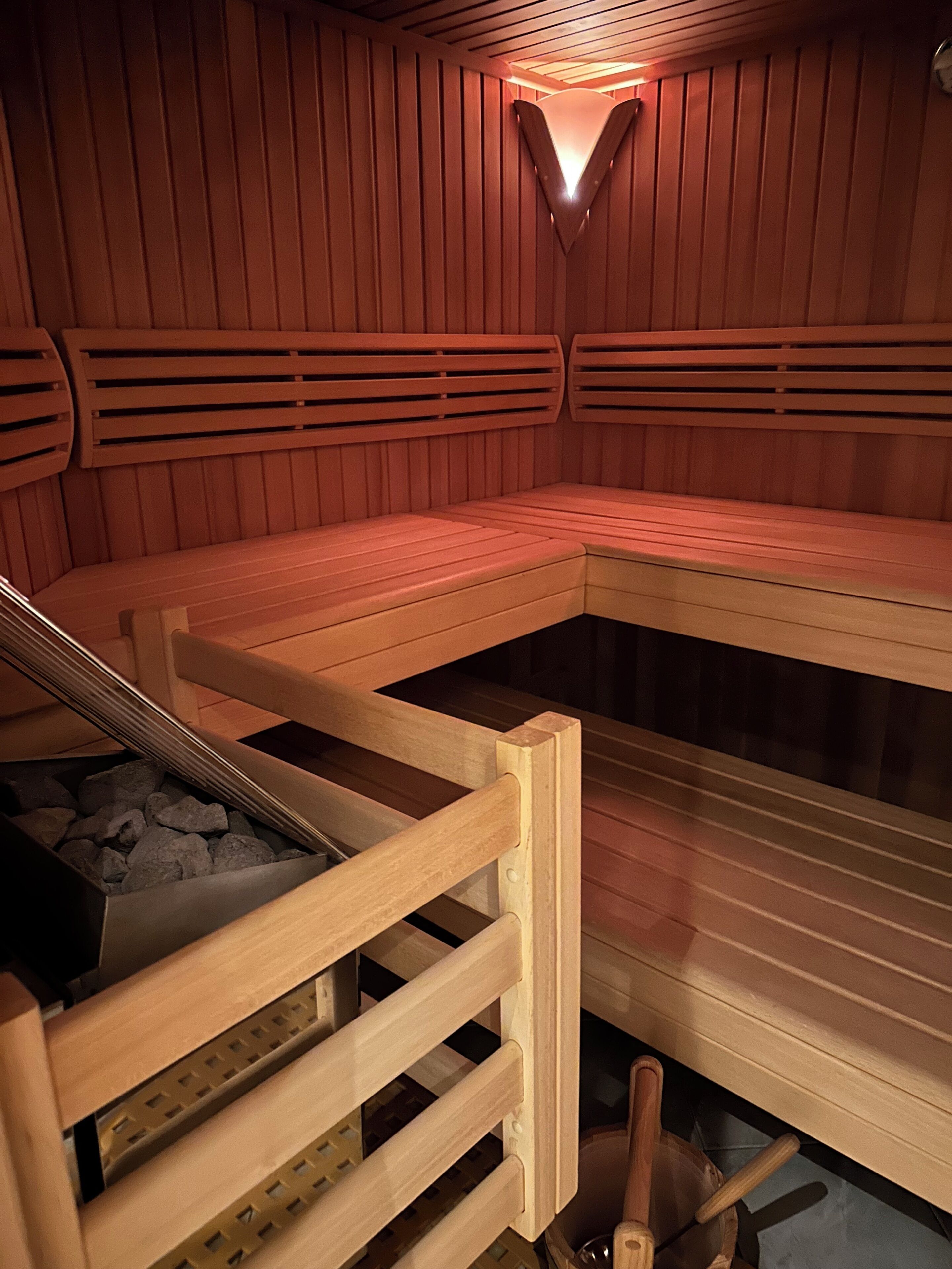 A sauna with benches and a stone-filled container, likely for heating.