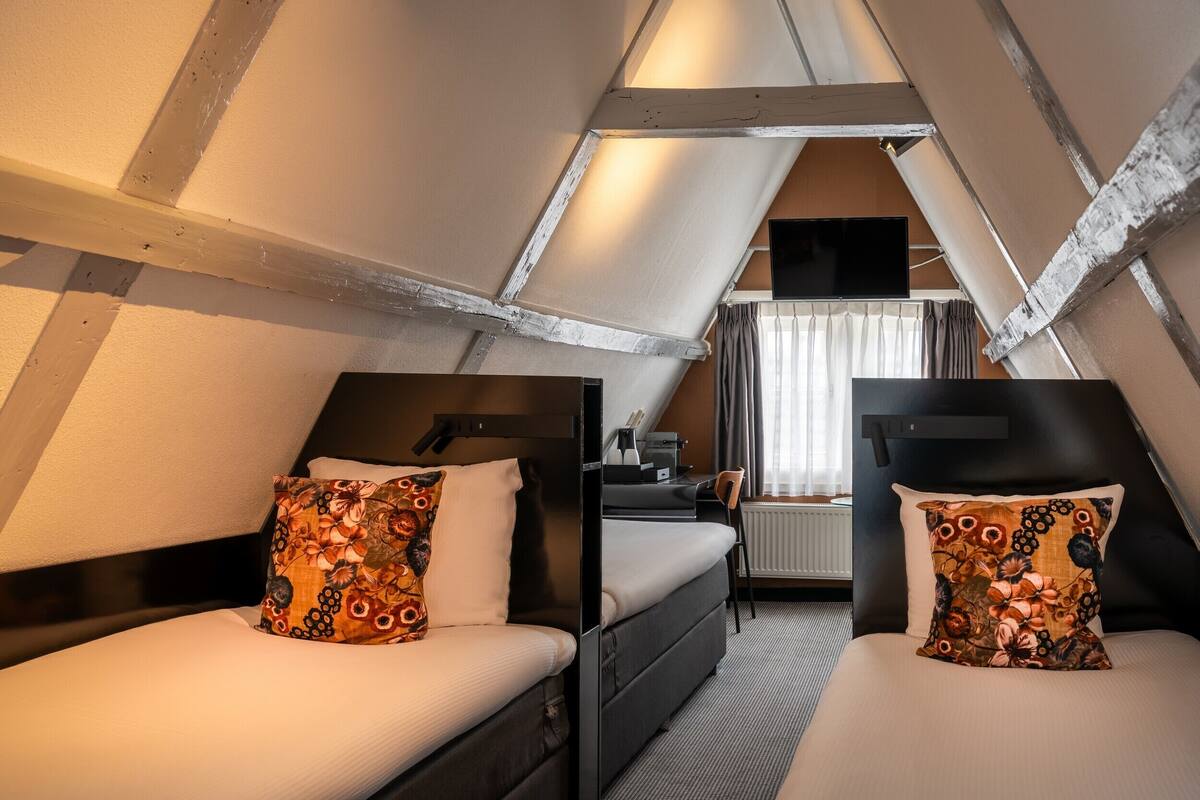 Een kamer met twee bedden, een bureau, een stoel en een raam met gordijnen.