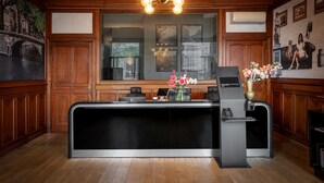 A reception desk with a modern design, wooden paneling, and a large window with a view of a bridge. - Hotel Mansion (Amsterdam)