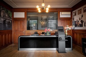 Un comptoir d’accueil au design moderne, avec un revêtement mural en bois et une grande fenêtre donnant sur un pont.