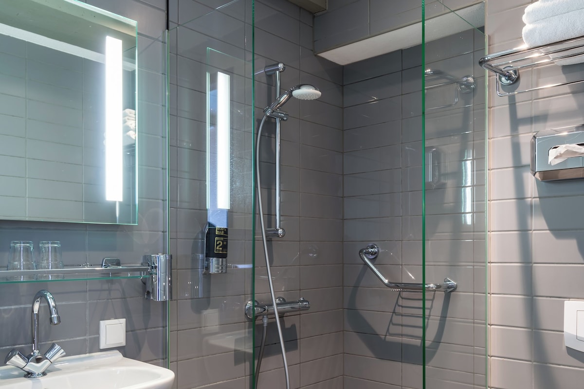 A modern bathroom with a glass-enclosed shower, a white sink, and a toilet.