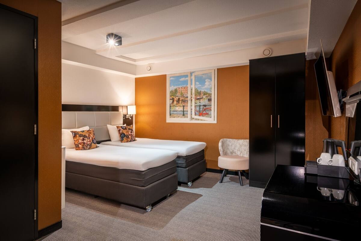 Een hotelkamer met een bed, een stoel, een bureau met koffiezetapparaat en een televisie.