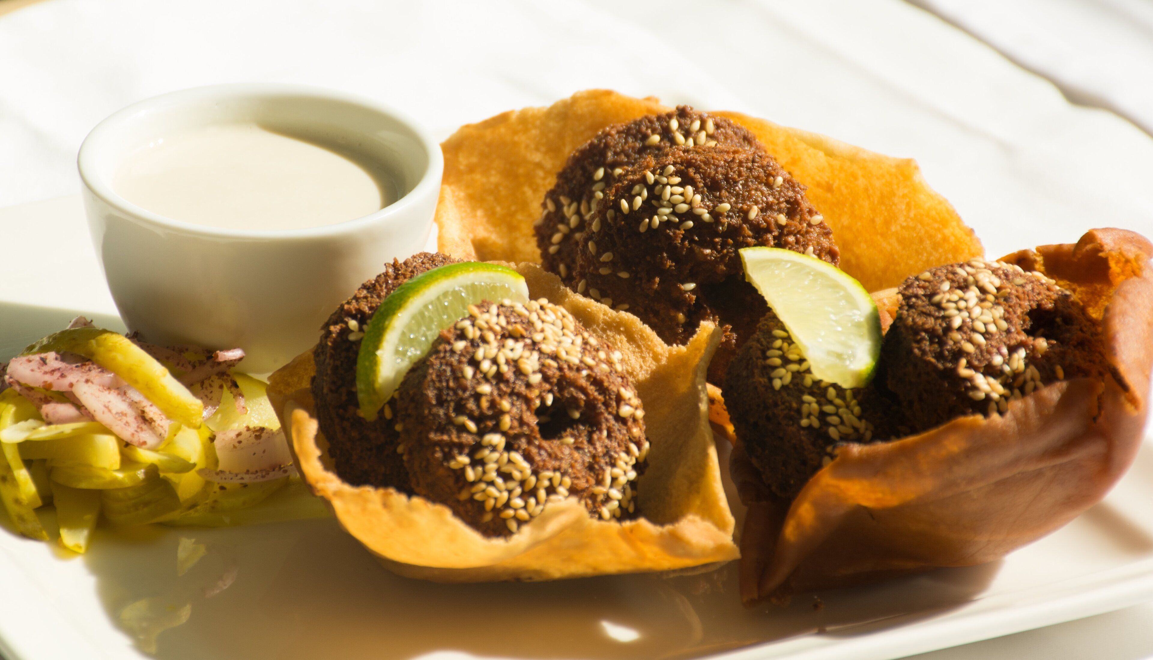 A plate with falafel balls, a side salad, and a small bowl of sauce.
