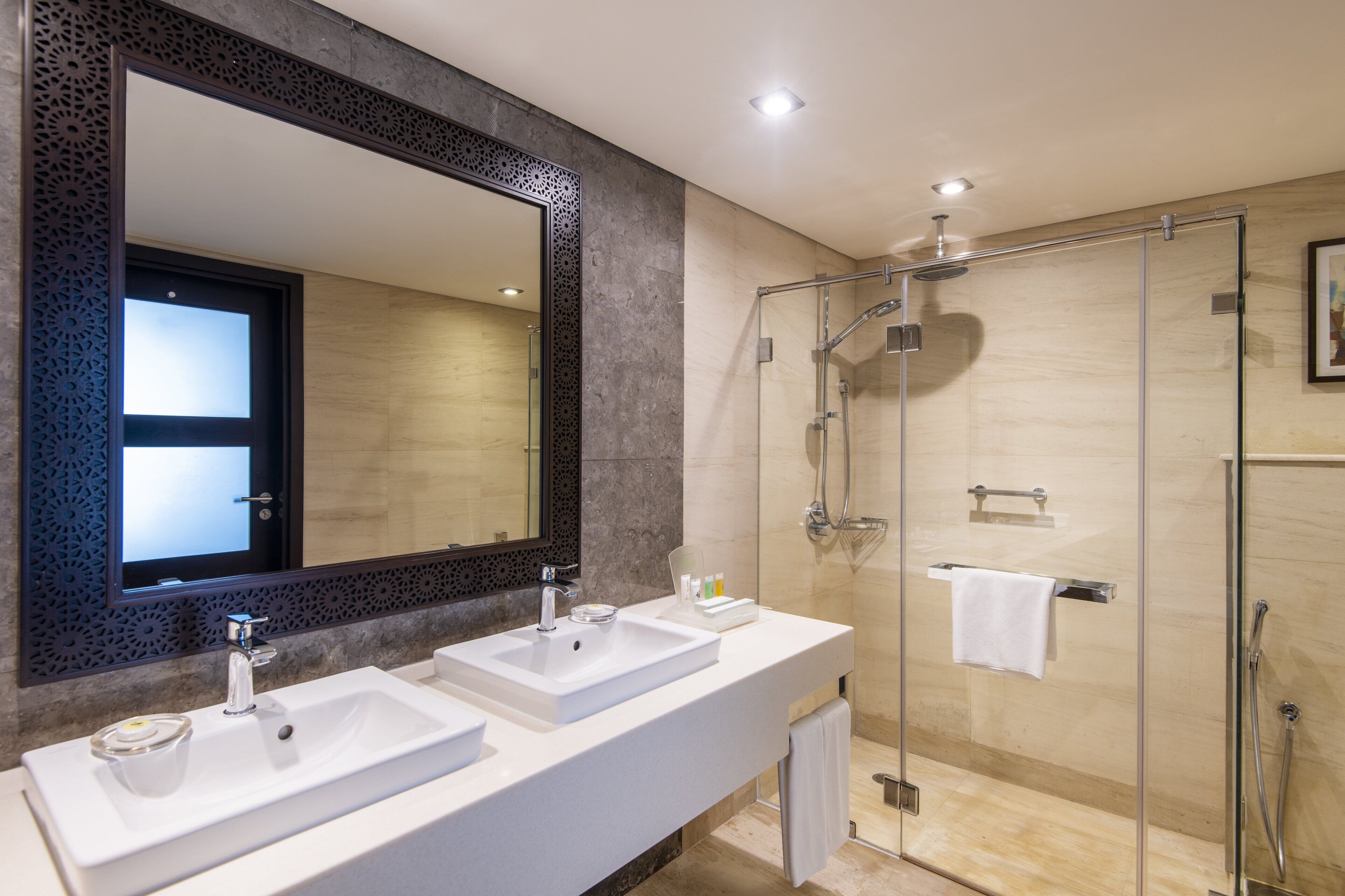 Un baño moderno con dos lavamanos, un espejo grande y una ducha con paredes de vidrio.