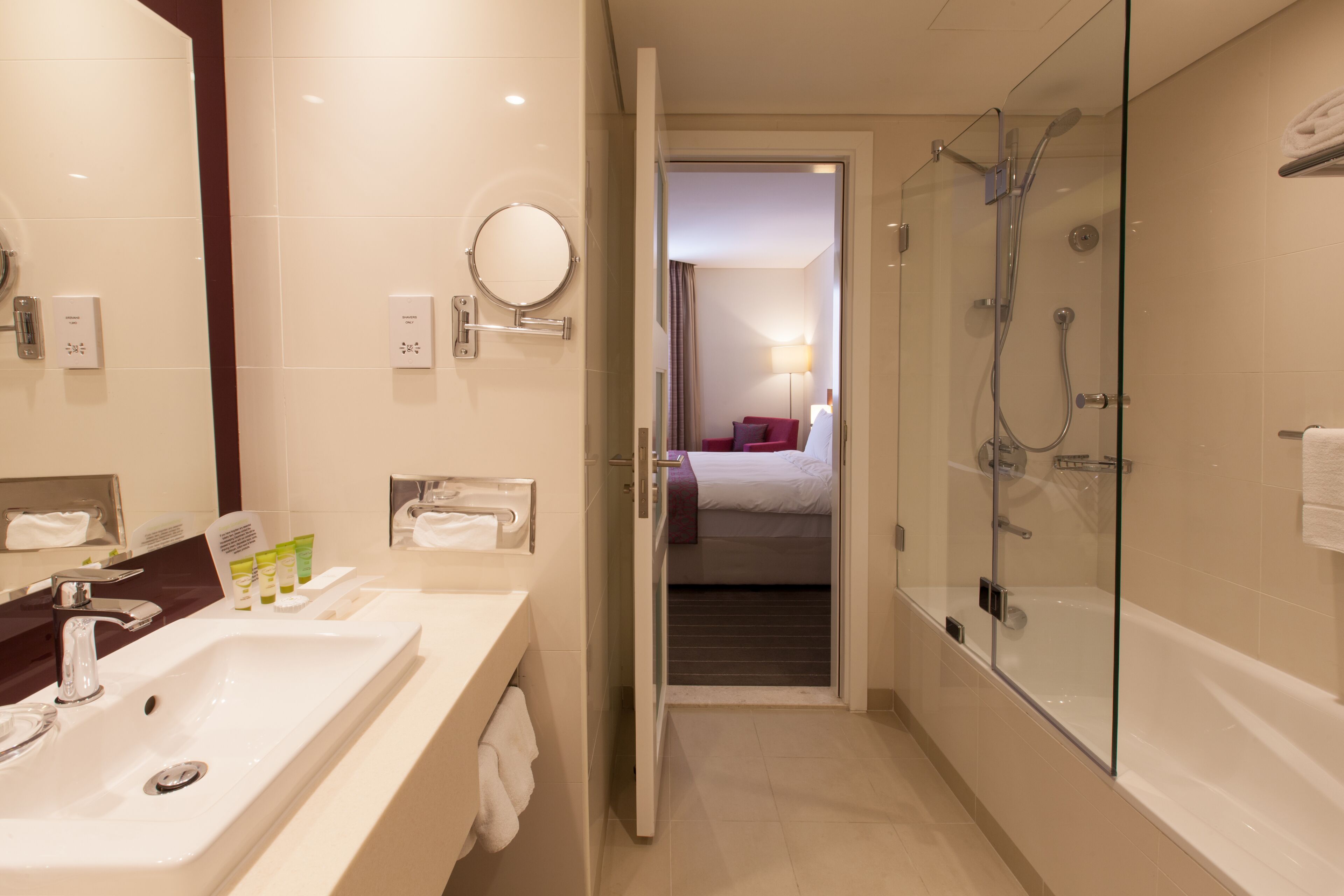 A modern bathroom with a sink, mirror, and glass shower enclosure.