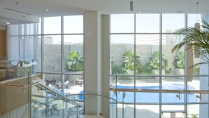 A spacious indoor area with large windows, a glass railing, and a view of an outdoor swimming pool.