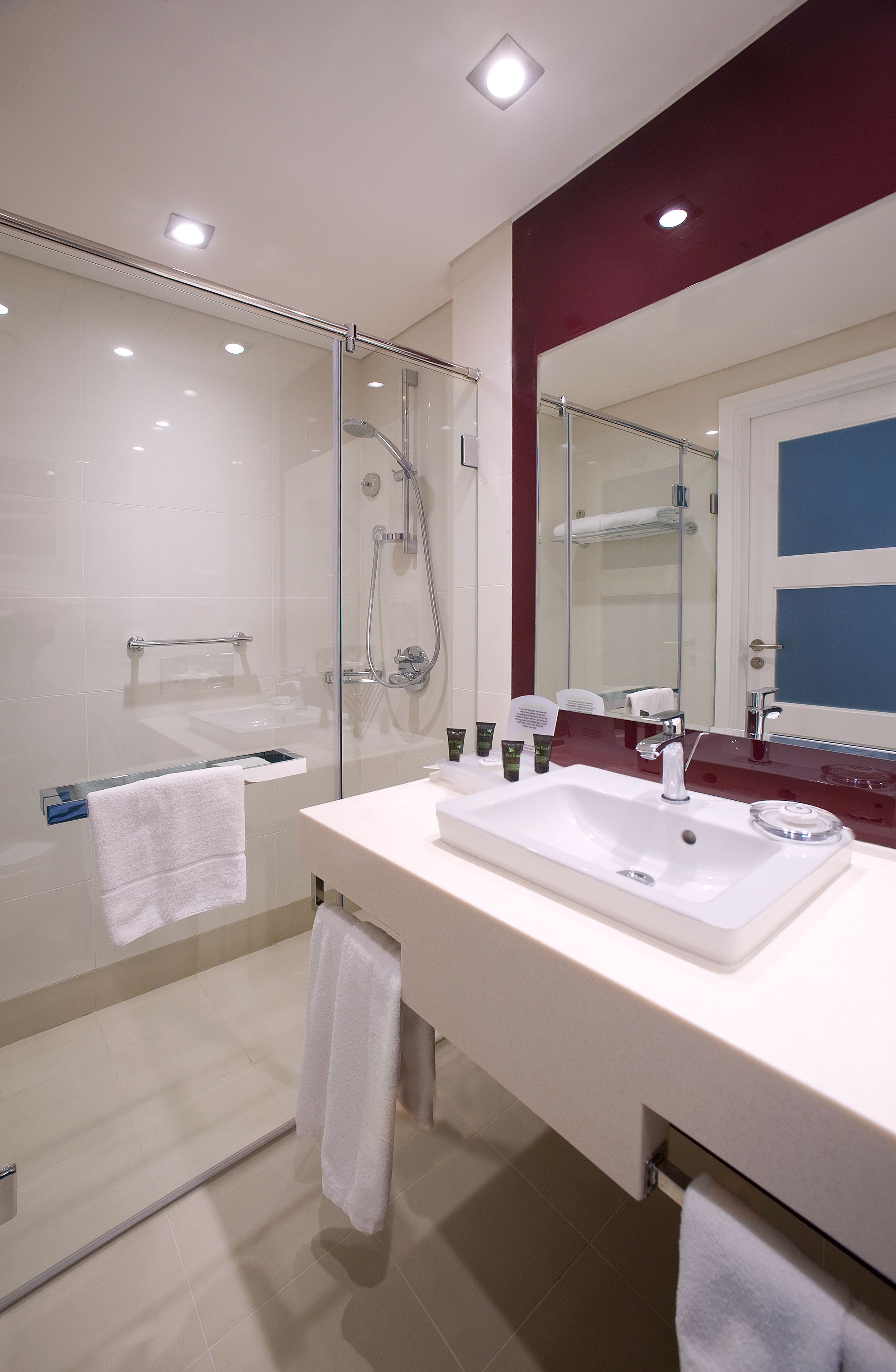 A modern bathroom with a glass-enclosed shower, a white sink, and a large mirror.