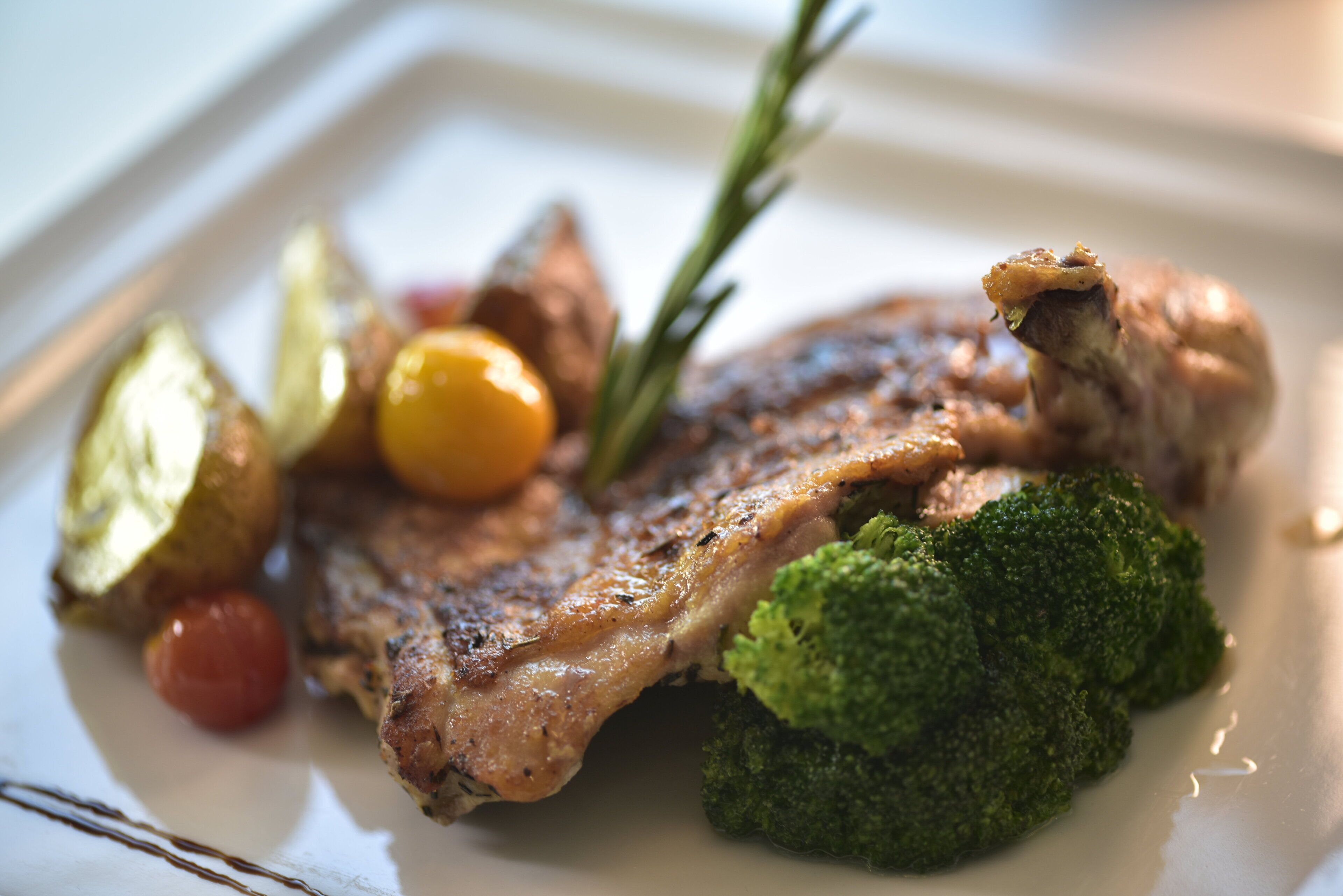 Un plato con carne a la parrilla, brócoli y tomates cherry.