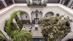 A courtyard with a pool, palm trees, and a seating area with a table and chairs. - Riad Braya  (Fès)
