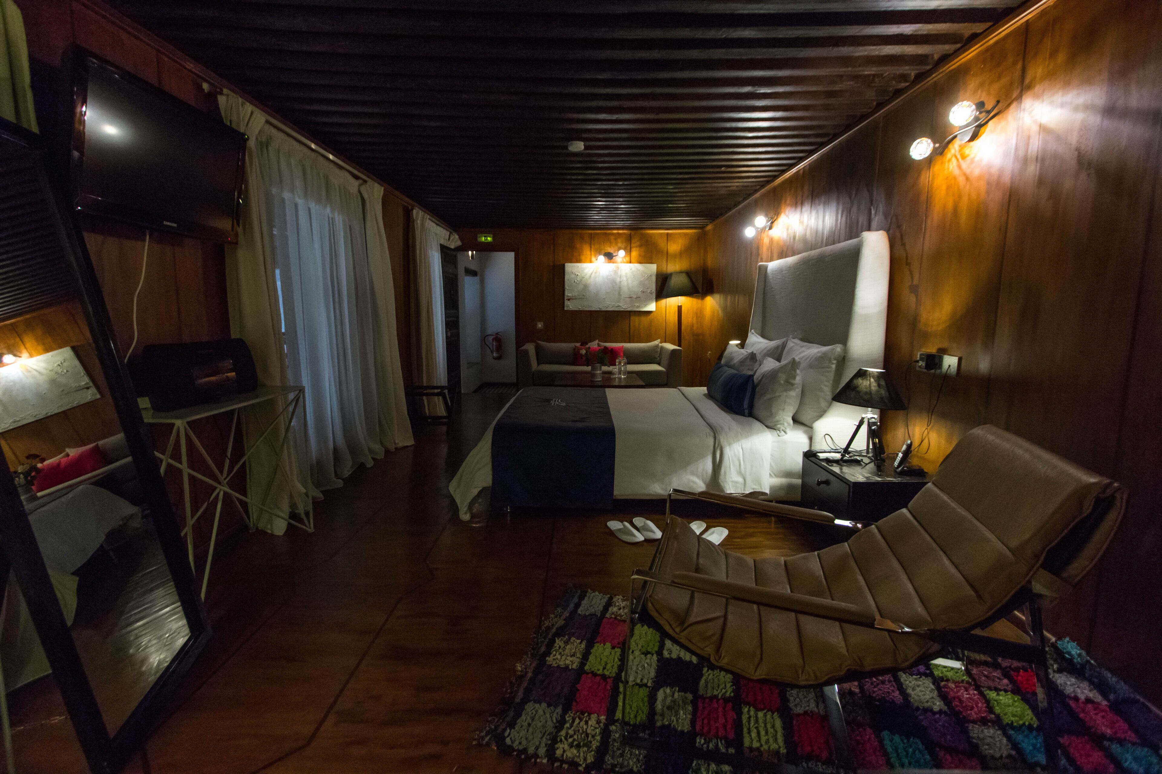 Una habitación acogedora con una cama, un sillón, una mesita y un televisor.