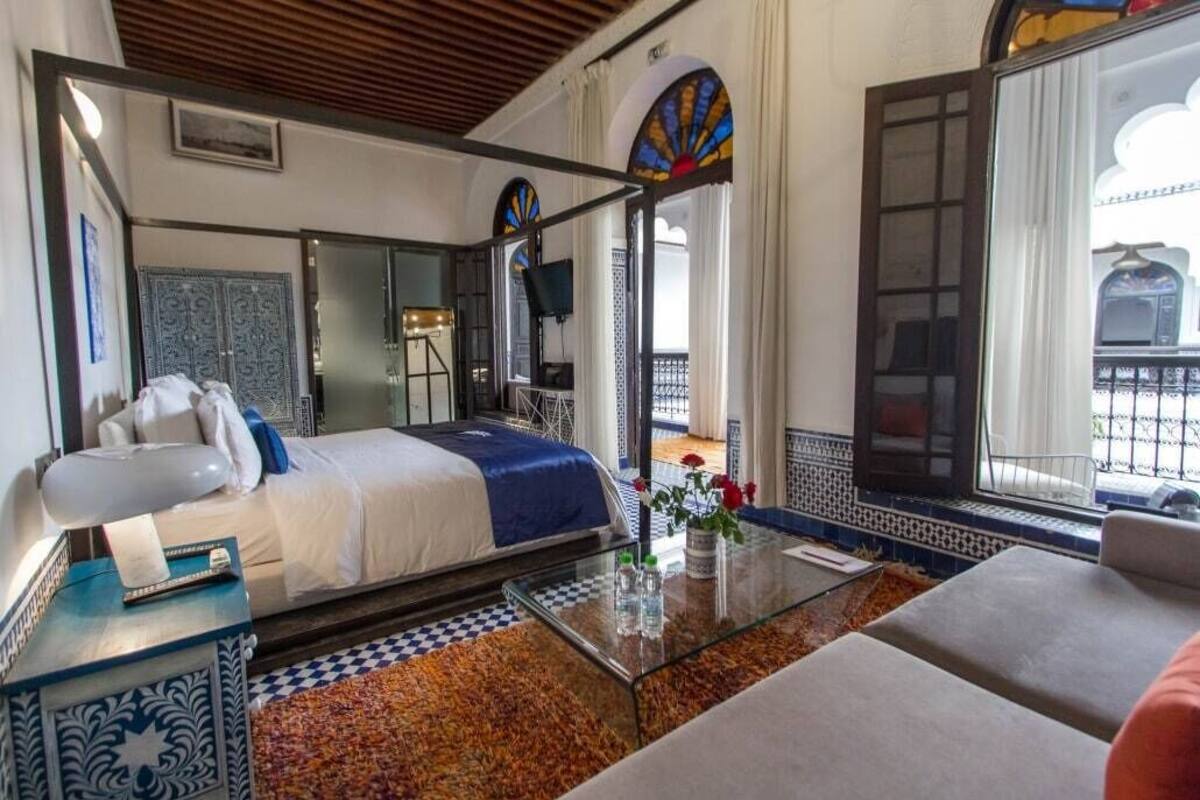 A hotel room with a bed, a glass coffee table, a sofa, and a balcony with a view.