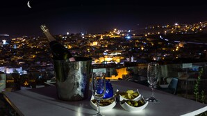 A table with a bottle of champagne, a glass, and bowls of olives and olives in a city view at night. - Riad Braya  (Fès)
