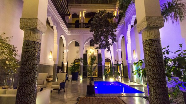 A luxurious lobby with a central pool, ornate columns, and comfortable seating areas. - Riad Braya  (Fès)