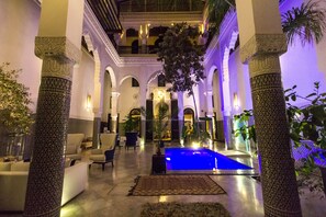 A luxurious lobby with a central pool, ornate columns, and comfortable seating areas. - Riad Braya  (Fès)
