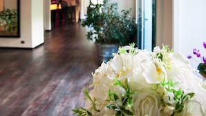 Un pasillo con suelo de madera, una planta en maceta y un arreglo floral blanco.
