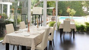 Comedor con una mesa dispuesta para seis personas, sillas alrededor y techo de cristal que deja entrar luz natural.
