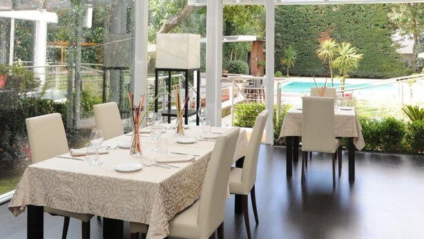 Comedor con una mesa dispuesta para seis personas, sillas alrededor y techo de cristal que deja entrar luz natural.