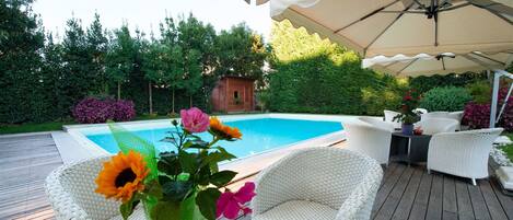 A wooden deck with wicker furniture and a pool.