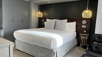 Un dormitorio moderno con una cama grande, un armario gris y una mesita redonda con un teléfono.
