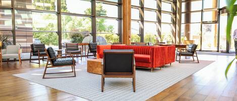 A spacious room with large windows, a red sofa, and several chairs.