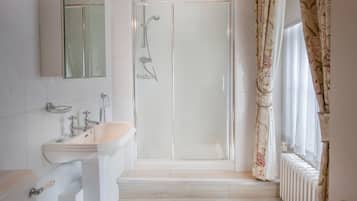 A bathroom with a glass-enclosed shower, a sink, and a mirror.