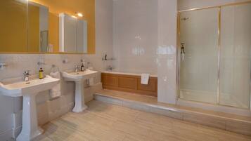 A bathroom with two sinks, a bathtub, and a glass-enclosed shower.
