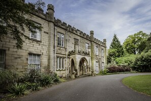 A historic stone building with arched windows and a curved driveway.