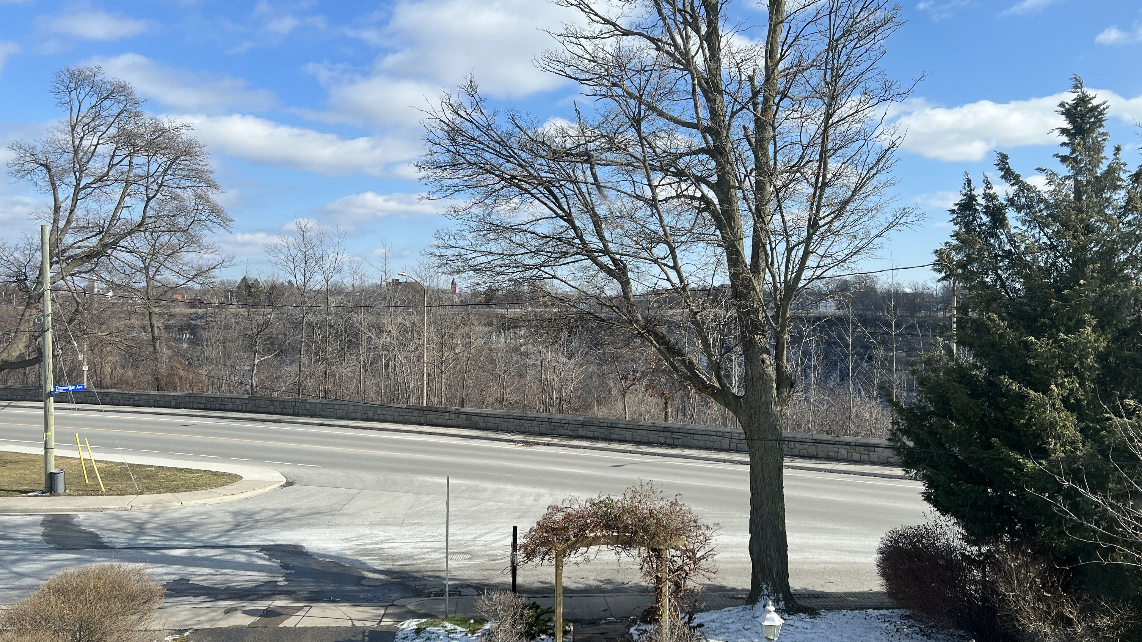 Eine gewundene Straße, eine Steinmauer und kahl stehende Bäume.