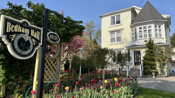 A sign for Bedham Hall, a house with a gabled roof, and a garden with tulips. - Bedham Hall Bed & Breakfast (Niagara Falls)