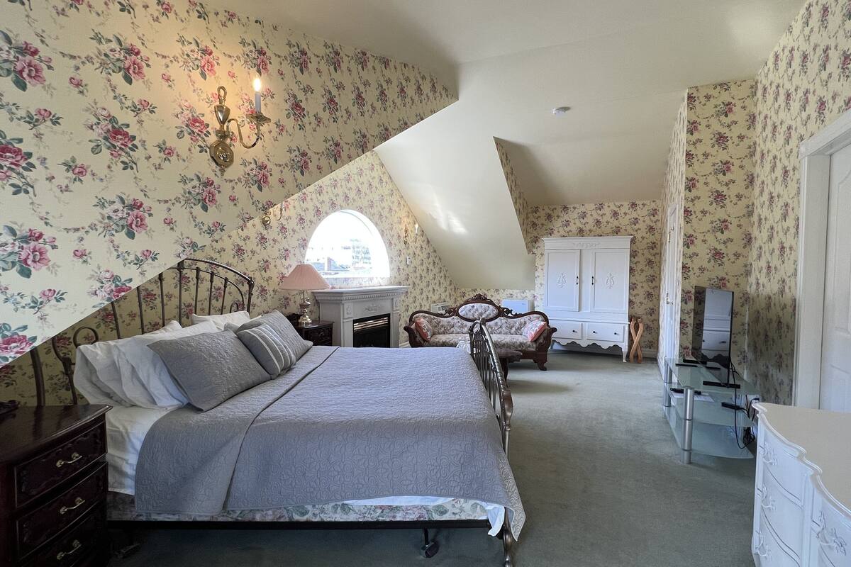 A bedroom with a bed, dresser, vanity, and a mirror.