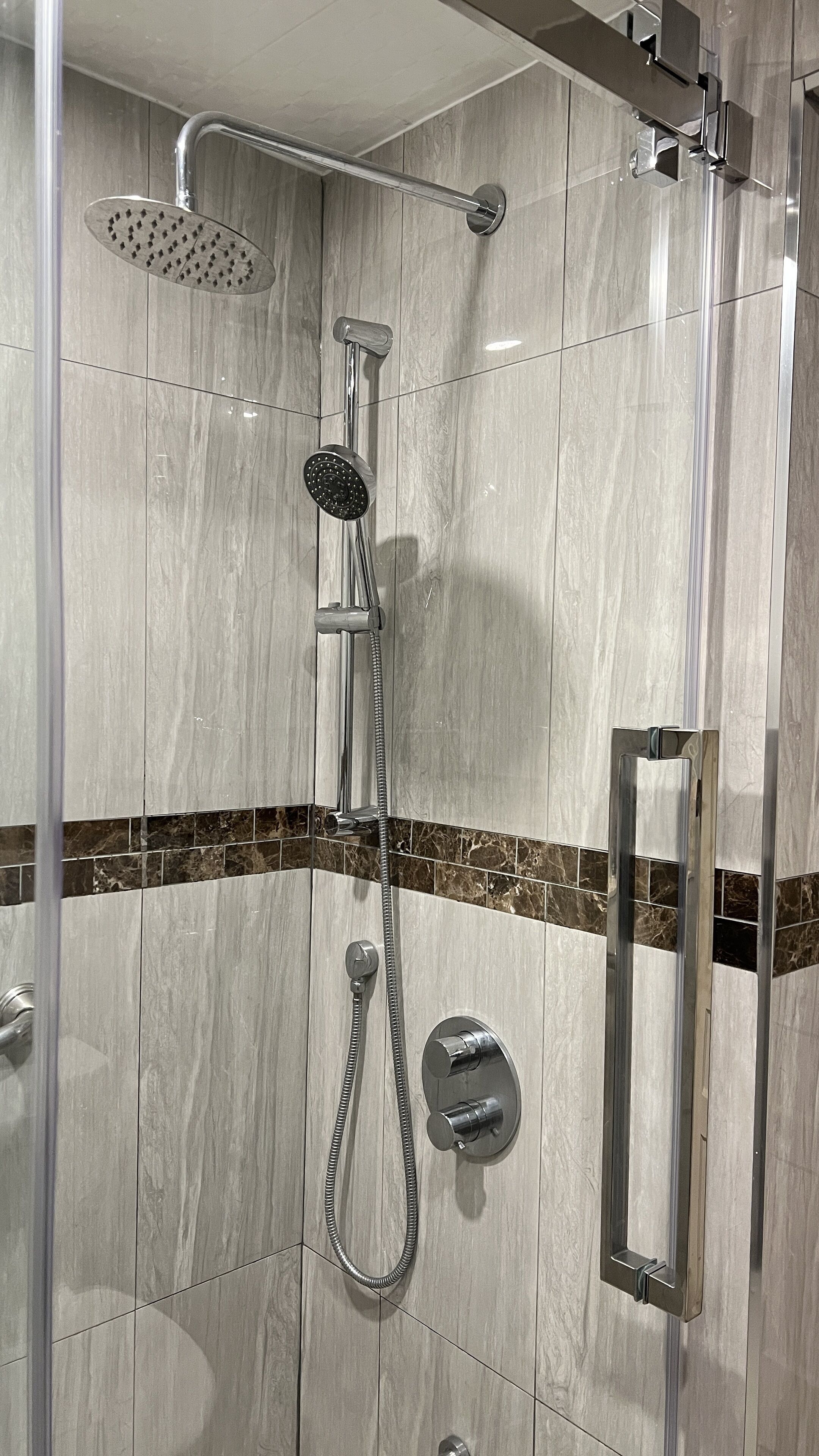 Eine Dusche mit Duschkopf, Handbrause und Duschschlauch.