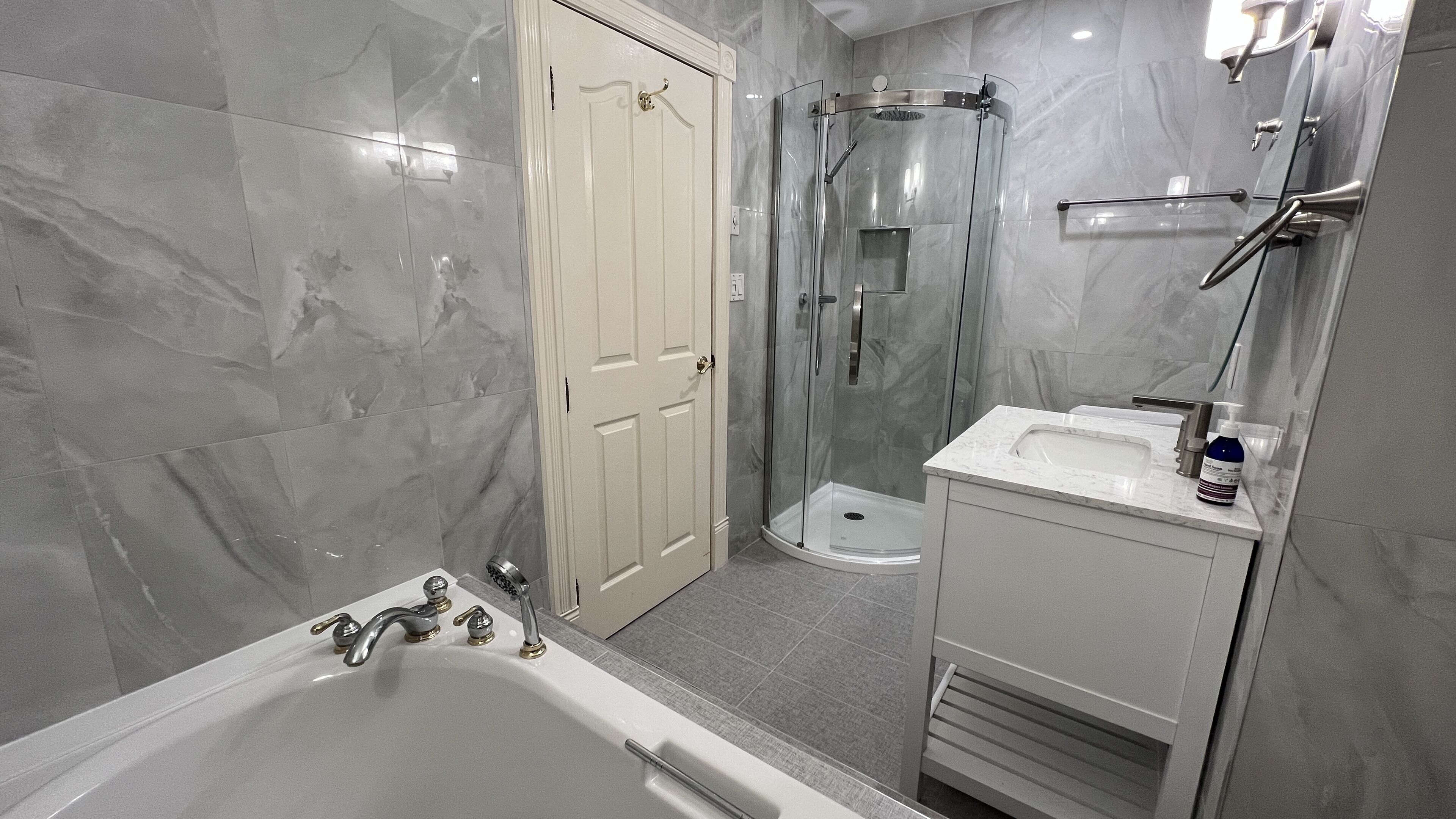 A modern bathroom with a bathtub, a glass-enclosed shower, and a vanity with a sink.