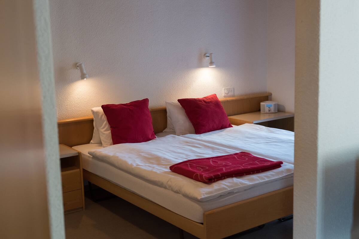 A single bed with a wooden headboard, two bedside tables, and two wall-mounted reading lamps.