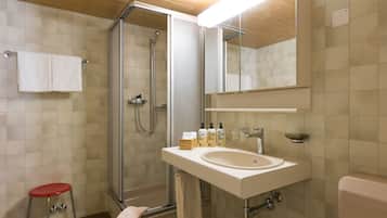 A modern bathroom with a glass-enclosed shower, a white sink, and a mirror above it.
