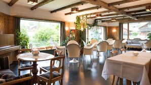 Comedor con vigas de madera, mesas redondas y sillas.