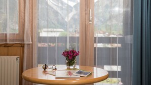 Una mesa redonda de madera con un florero de flores rosas, un par de gafas y una revista.