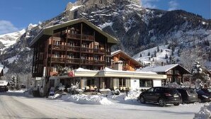 Un albergue de montaña con varios pisos, un telesilla y un paisaje nevado.
