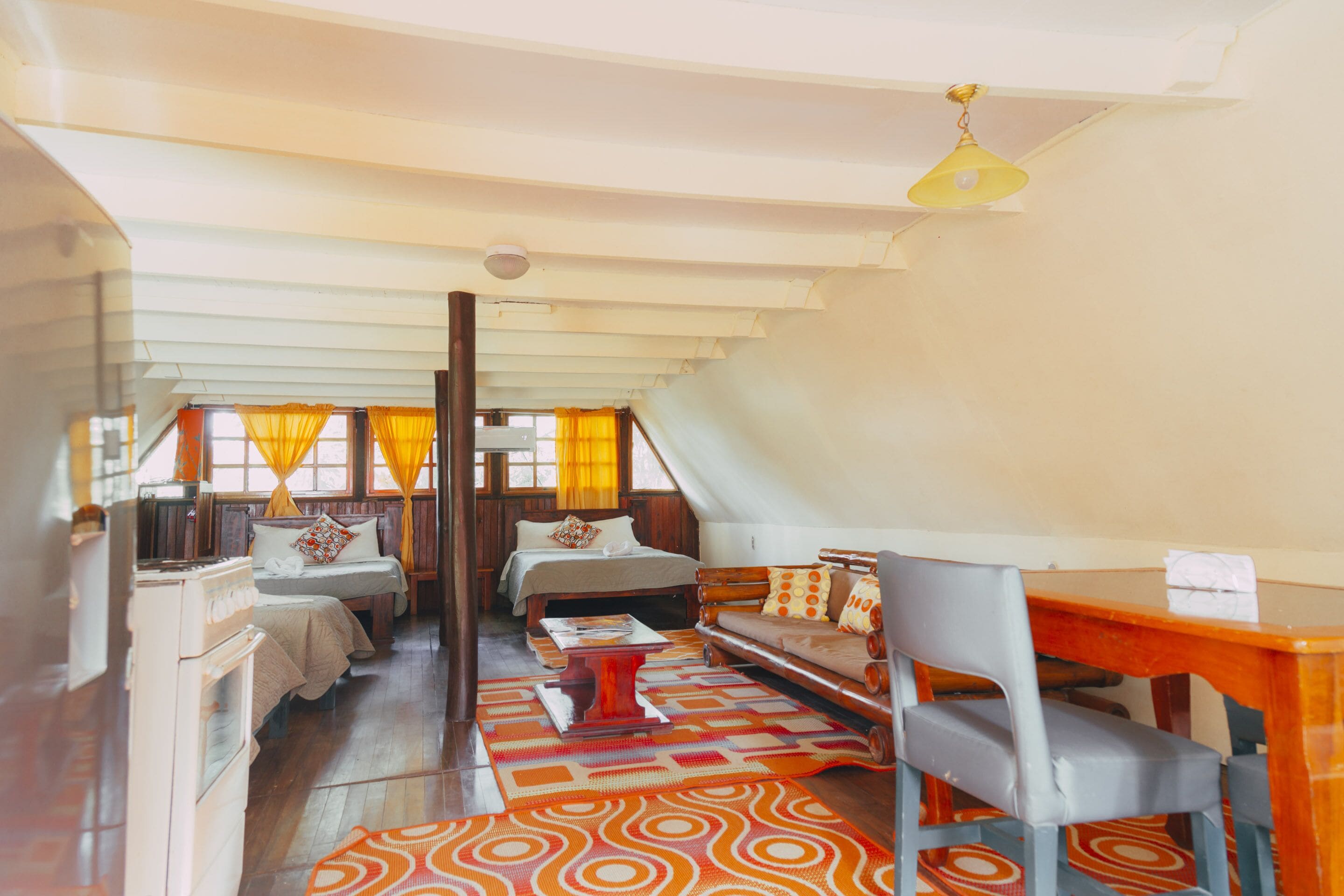 A cozy room with a bed, a sofa, a dining table, and a kitchen area.