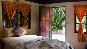 Une chambre à coucher avec un lit, des rideaux et une porte donnant sur un espace extérieur.