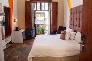Een hotelkamer met een bed, een bureau, een stoel en een tafeltje.