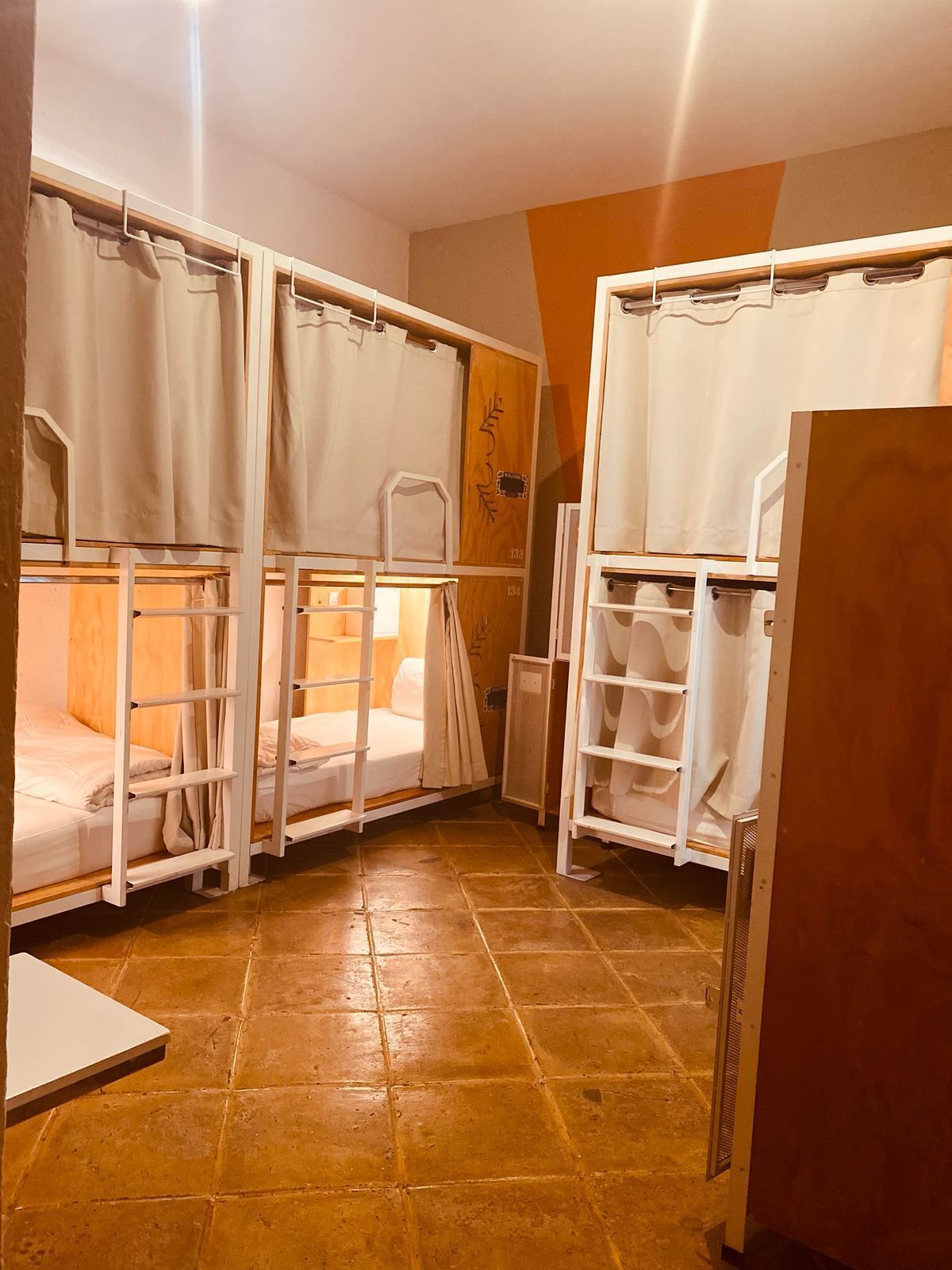 A dormitory room with bunk beds, a small table, and a cabinet.