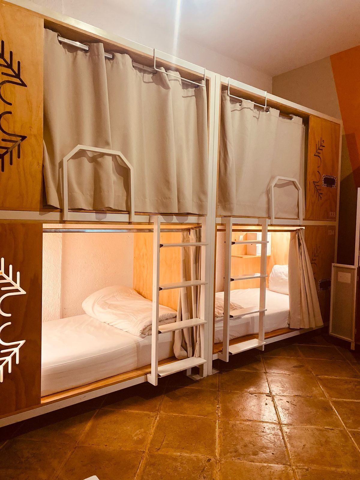 Dormitorio con literas, diseño de pared de madera, un escritorio pequeño y suelo de baldosas.