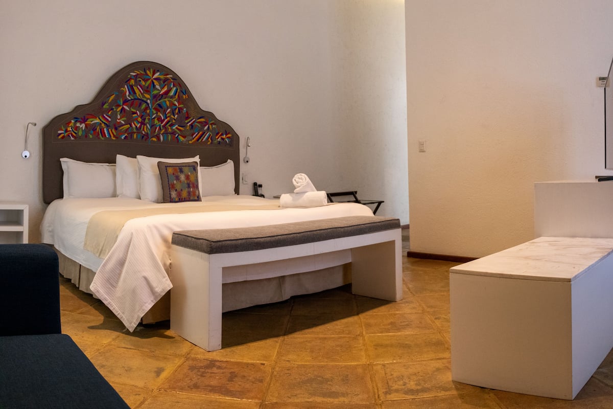 Una habitación de hotel moderna con una cama grande, un banco y una pequeña mesa.